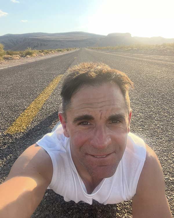 Paul McCabe lying on a quiet Route 66 road in Arizona during a personal burnout recovery journey and period of reflection.